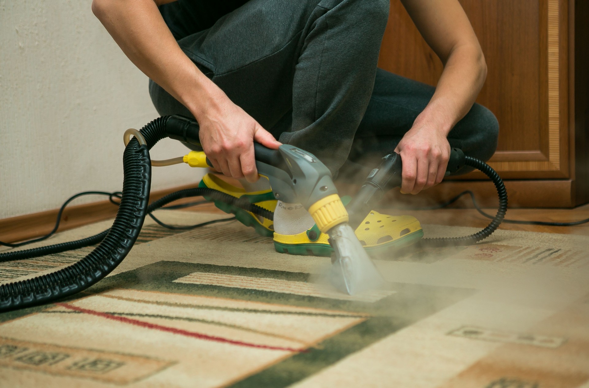 The process of cleaning carpets with a steam vacuum cleaner. An employee of a cleaning company cleans the carpet using steam.